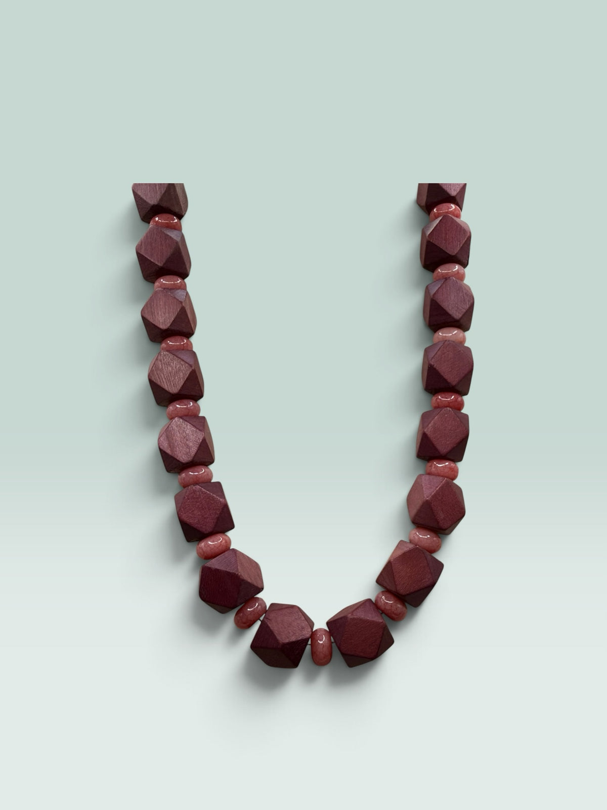 The Salty Bead Co geometric wooden necklace featuring faceted dark mahogany and smooth dusty rose beads.