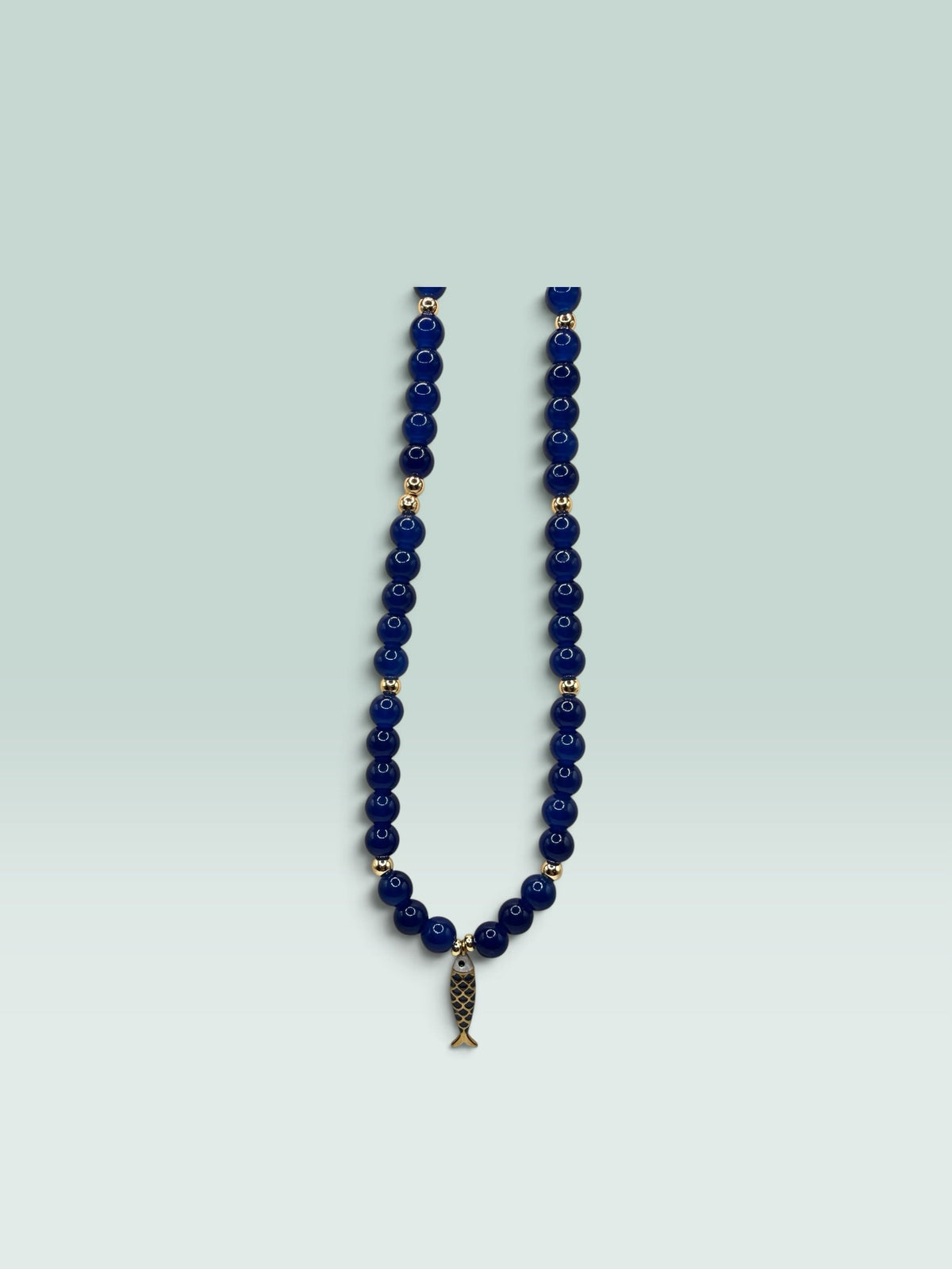 The Salty Bead Co navy blue beaded necklace with gold-tone spacers and a whimsical fish charm pendant.