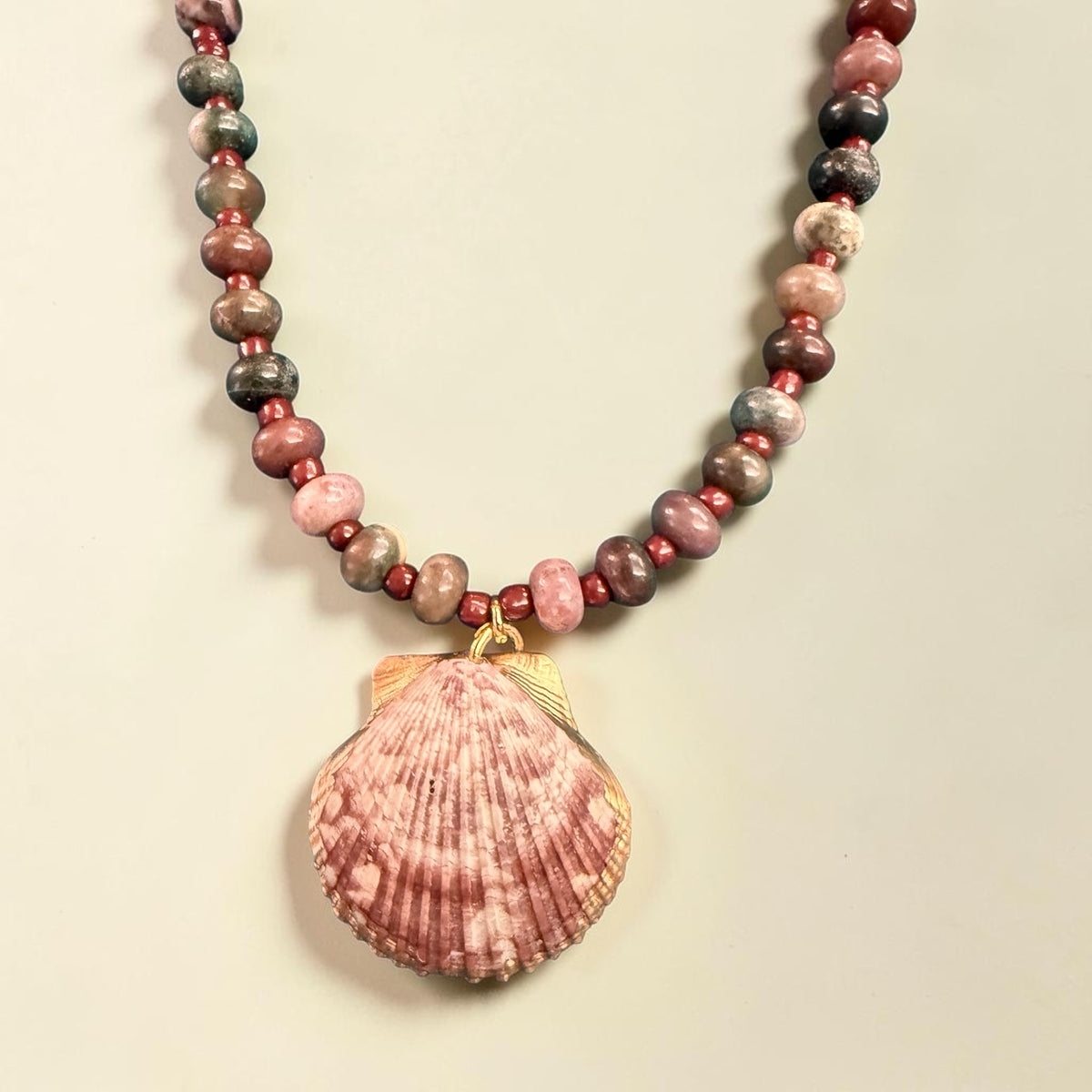 The Salty Bead Co handcrafted necklace with a natural seashell pendant and dusty rose and grey semi-precious beads.