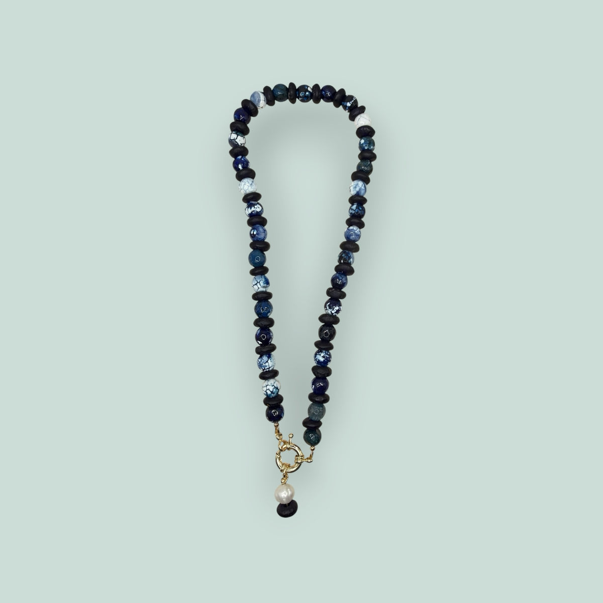 The Salty Bead Co artisan necklace with navy and marbled blue agate beads, matte black spacers, and a gold-tone clasp.