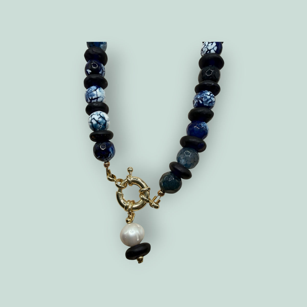 The Salty Bead Co artisan necklace with navy and marbled blue agate beads, black spacers, and a gold clasp with pearl