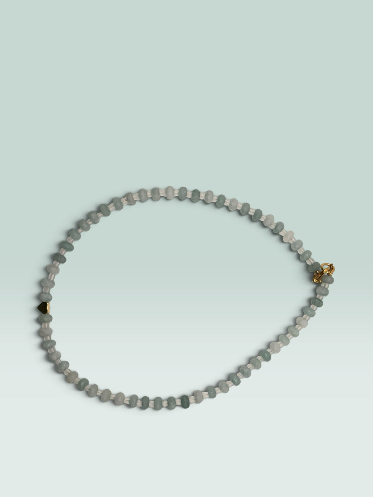 The Salty Bead Co beaded necklace with aquamarine-toned faceted beads, clear spacers, and a gold-tone heart charm.