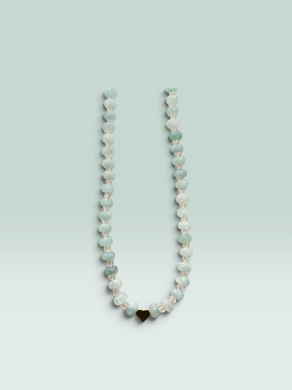 The Salty Bead Co beaded necklace featuring faceted aquamarine-toned beads and a polished gold-tone heart charm.