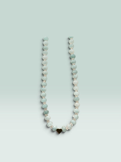 The Salty Bead Co beaded necklace featuring faceted aquamarine-toned beads and a polished gold-tone heart charm.