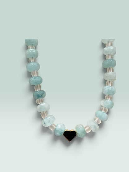 The Salty Bead Co beaded necklace with aquamarine-toned faceted beads, clear spacers, and a gold-tone heart charm.