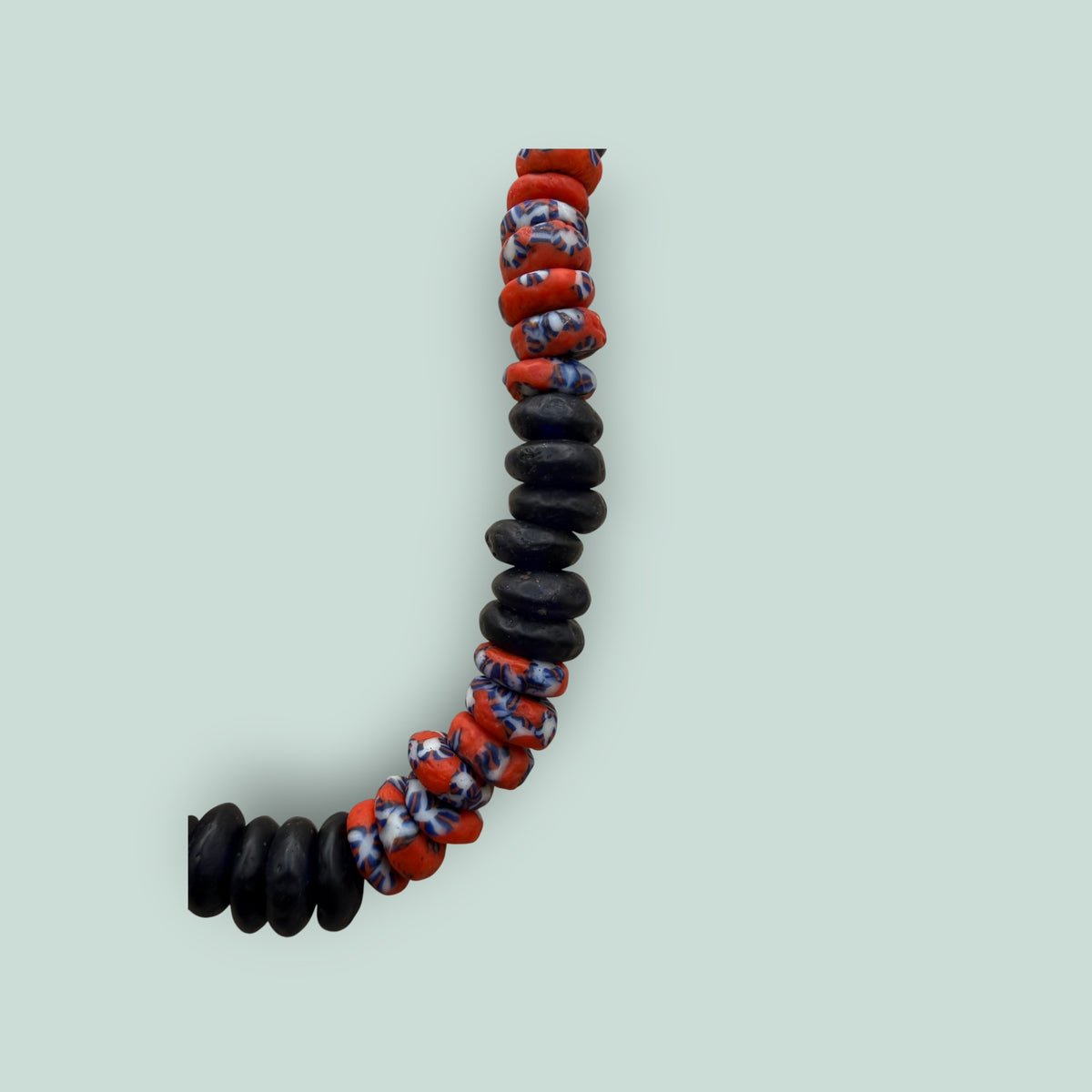 The Salty Bead Co handcrafted necklace with matte black disc beads and vibrant red and blue patterned glass beads.