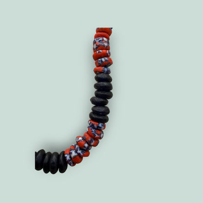 The Salty Bead Co handcrafted necklace with matte black disc beads and vibrant red and blue patterned glass beads.