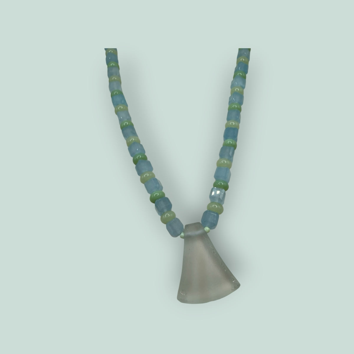 The Salty Bead Co handcrafted necklace with light blue and sage green glass beads and a frosted flared glass pendant.
