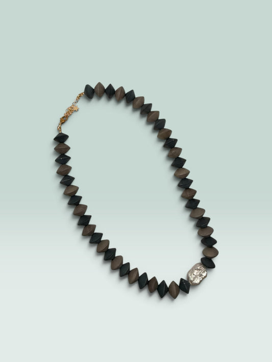 The Salty Bead Co handcrafted statement necklace with matte black and brown geometric beads and metallic accent.