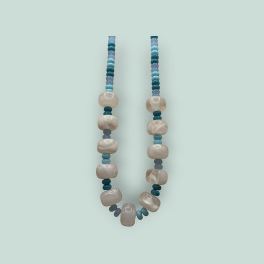 The Salty Bead Co handcrafted statement necklace with marbled cream beads and blue teal accents on a light background