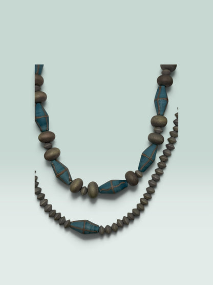 The Salty Bead Co handcrafted statement necklace featuring grey bicone beads and blue accents with metallic detailing.