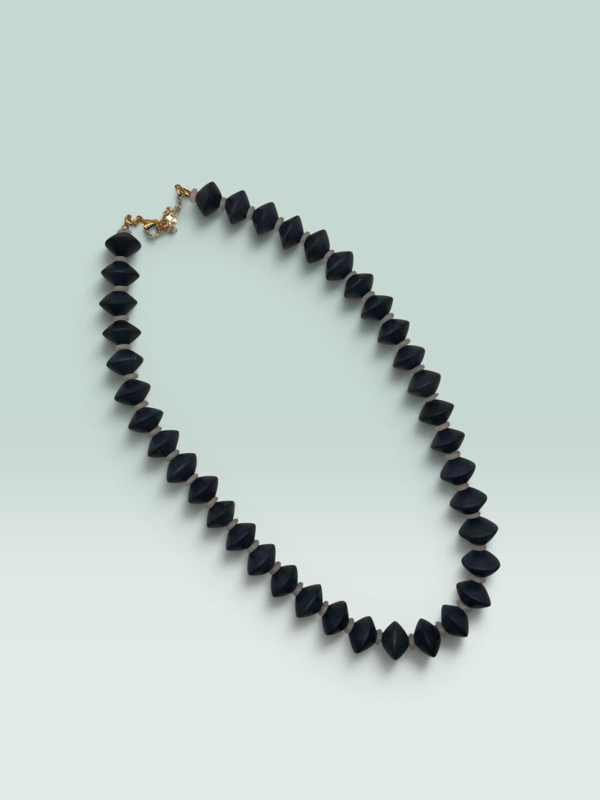 The Salty Bead Co statement necklace featuring matte black geometric bicone beads with neutral spacers