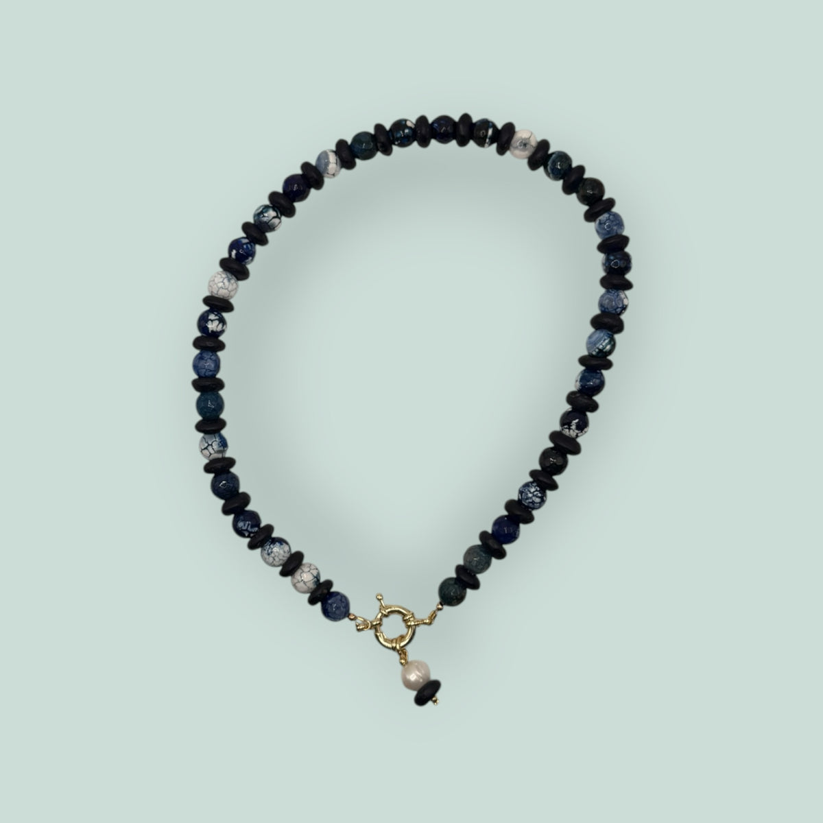 The Salty Bead Co artisan necklace with navy and marbled blue agate beads, matte black spacers, and a gold-tone clasp.
