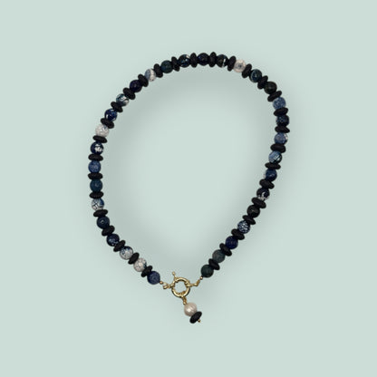 The Salty Bead Co artisan necklace with navy and marbled blue agate beads, matte black spacers, and a gold-tone clasp.