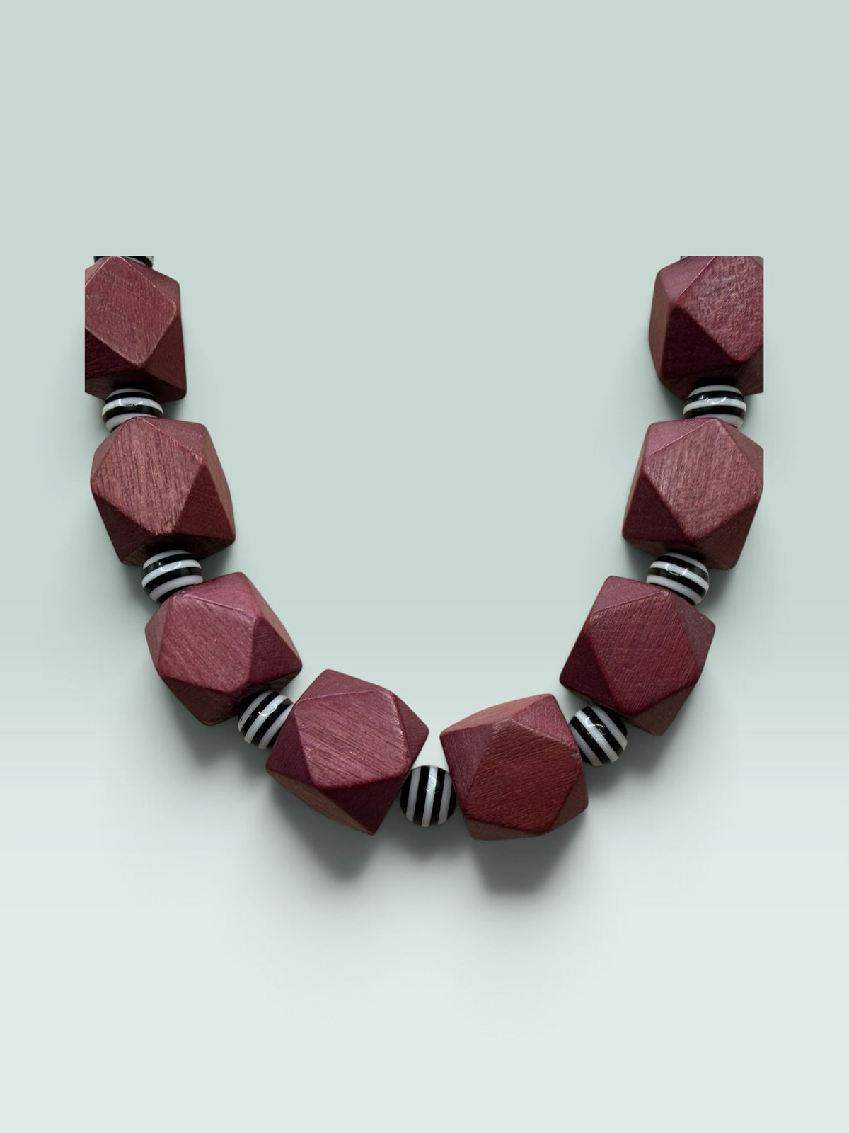 The Salty Bead Co geometric statement necklace featuring faceted burgundy wooden beads and black and white striped spacers