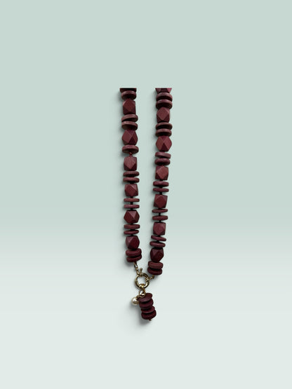 The Salty Bead Co handcrafted burgundy wooden bead statement necklace with a gold clasp and small pearl charm.