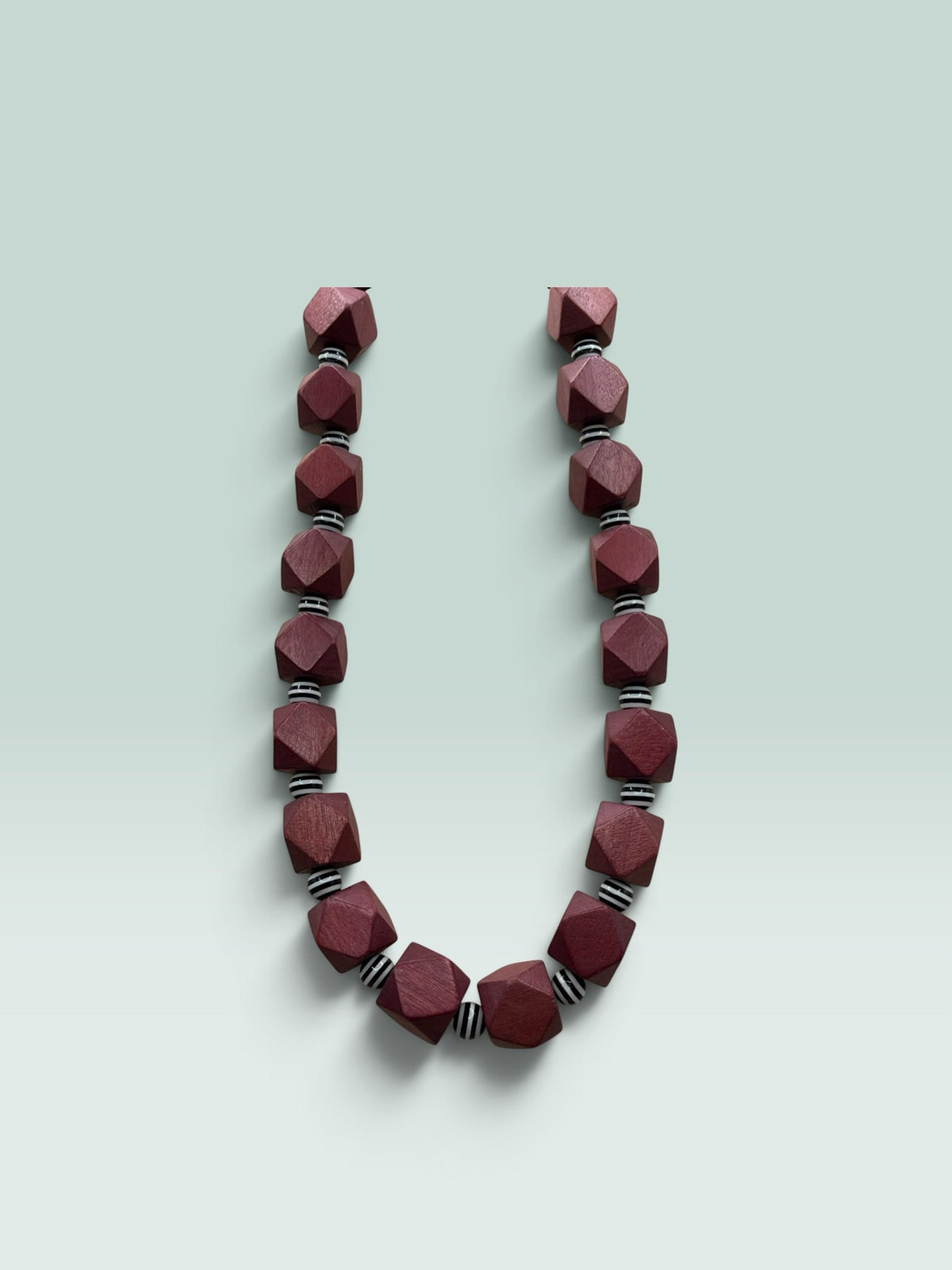 The Salty Bead Co geometric necklace featuring faceted burgundy wooden beads and black and white striped spacers.