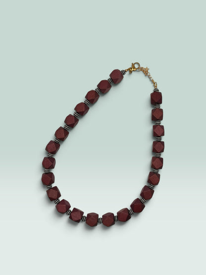 The Salty Bead Co geometric necklace featuring faceted burgundy wooden beads and black and white striped spacers.