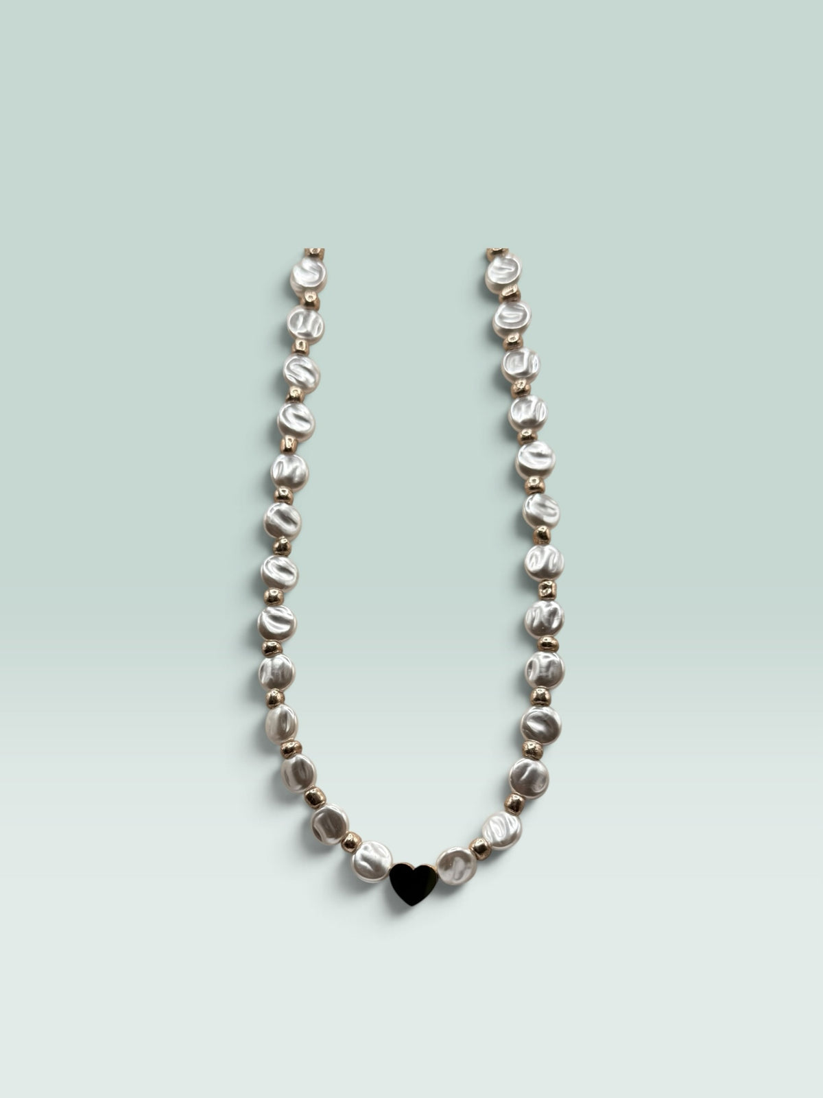 The Salty Bead Co necklace featuring lustrous coin pearls, metallic beads, and a minimalist black heart pendant.