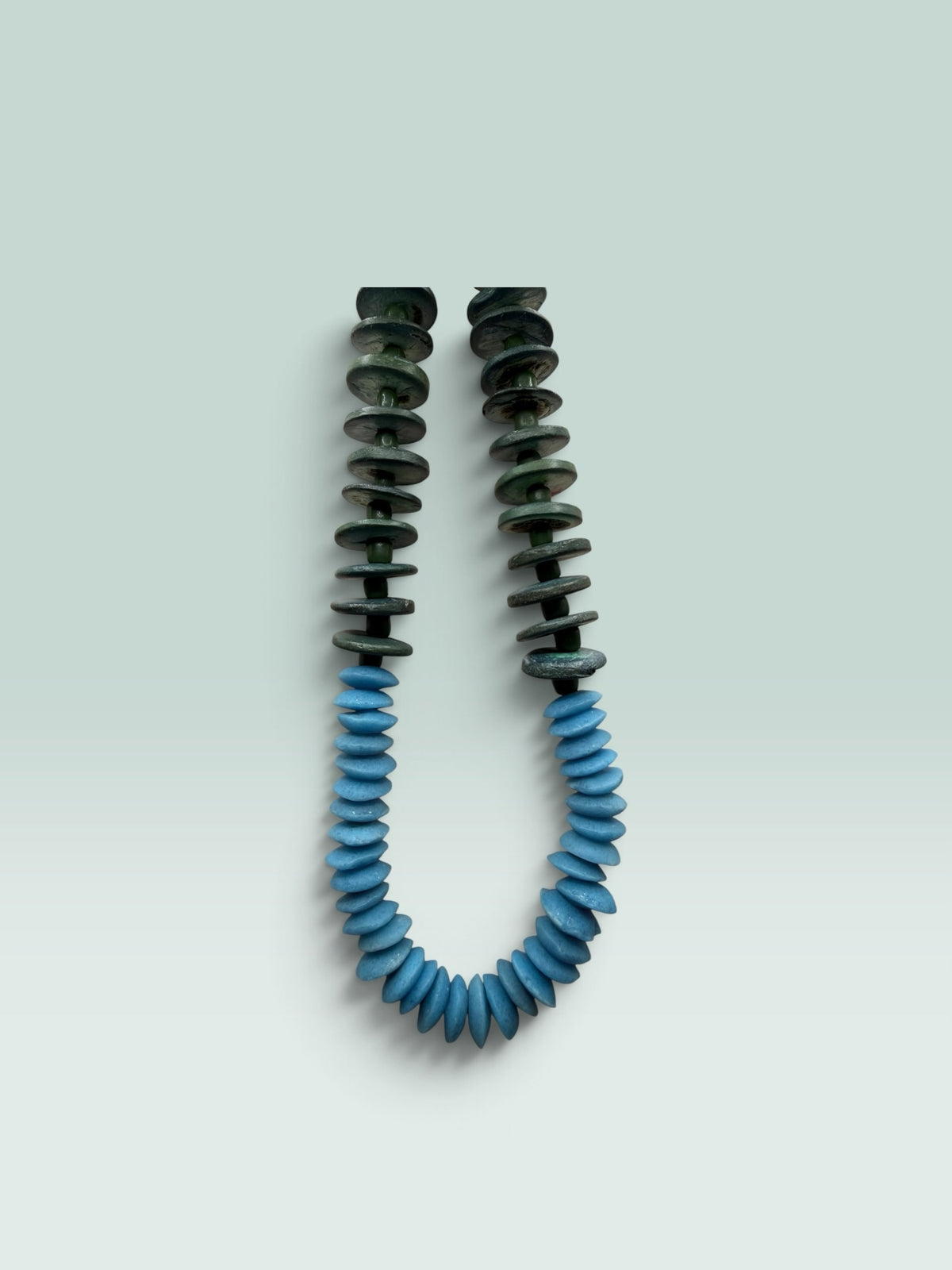 The Salty Bead Co handcrafted statement necklace featuring forest green and sky blue flattened disc beads.