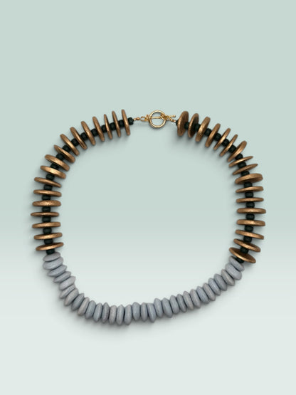The Salty Bead Co handcrafted statement necklace featuring metallic gold and slate-grey flattened disc beads with a toggle