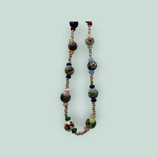 The Salty Bead Co handcrafted necklace featuring vibrant hand-painted ceramic floral beads and metallic spacers.