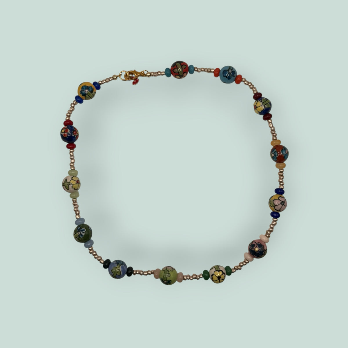 The Salty Bead Co handcrafted necklace featuring multi-colored floral ceramic beads and metallic spacer beads.