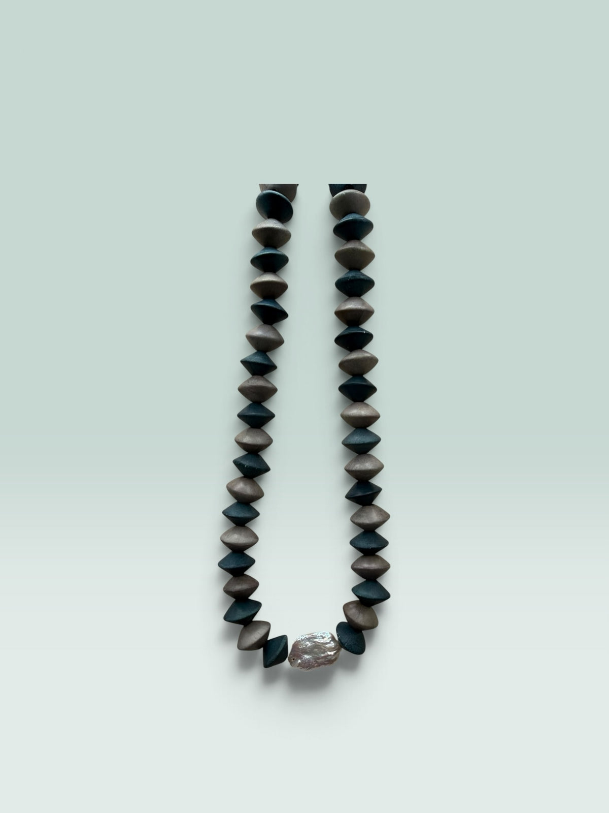 The Salty Bead Co handcrafted statement necklace with matte black and brown geometric beads and a metallic accent.