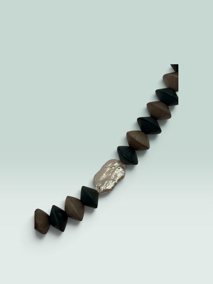 The Salty Bead Co handcrafted statement necklace with matte black and brown geometric beads and a metallic accent.