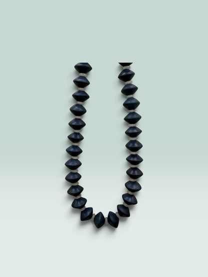 The Salty Bead Co handcrafted statement necklace featuring matte black geometric bicone beads with neutral spacers.