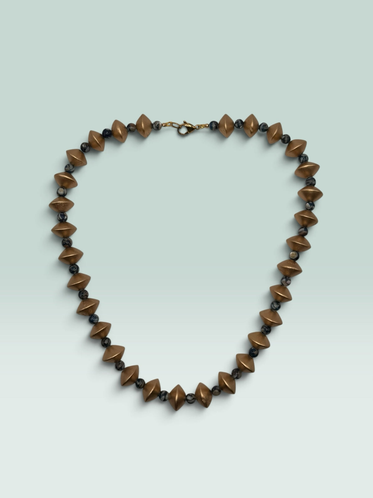 The Salty Bead Co geometric statement necklace featuring matte-gold diamond beads and dark marbled spheres.