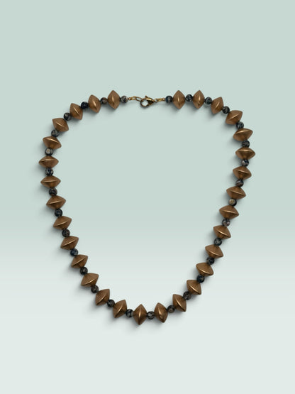 The Salty Bead Co geometric statement necklace featuring matte-gold diamond beads and dark marbled spheres.