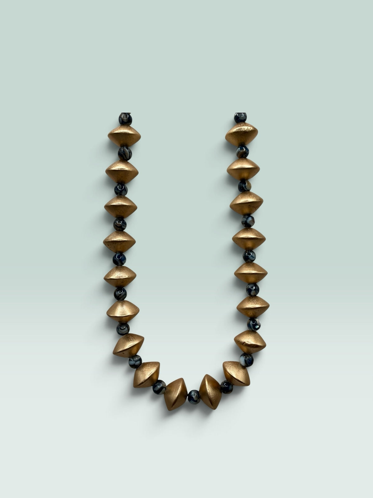 The Salty Bead Co statement necklace featuring matte gold geometric beads and dark marbled spheres on a light background