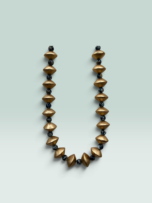 The Salty Bead Co statement necklace featuring matte gold geometric beads and dark marbled spheres on a light background