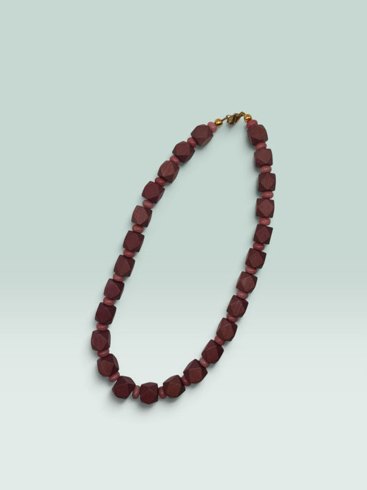 The Salty Bead Co geometric wooden bead necklace with faceted mahogany and dusty rose beads and a gold-tone clasp.