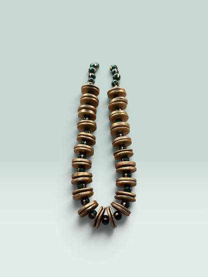 The Salty Bead Co artisan statement necklace featuring textured gold-toned discs and forest green beads
