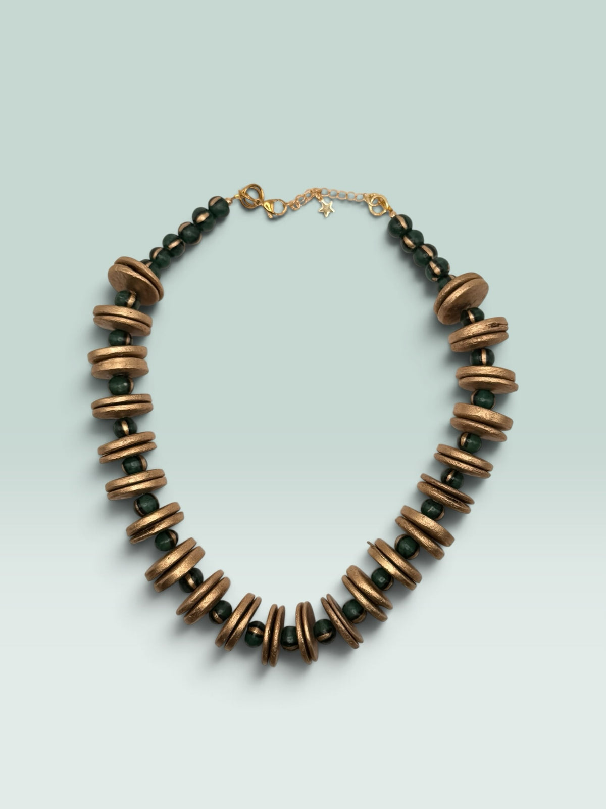 The Salty Bead Co artisan statement necklace featuring textured gold-toned discs and forest green beads on a chain.