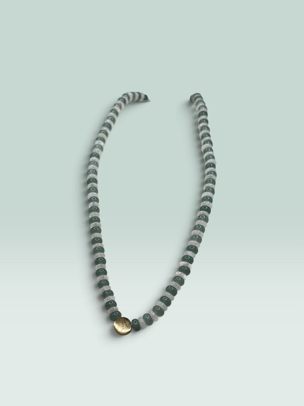 The Salty Bead Co beaded statement necklace with forest green and translucent grey beads and a gold-tone central charm.