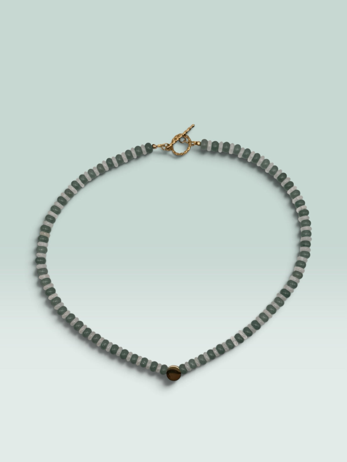 The Salty Bead Co beaded statement necklace with forest green and translucent grey beads and a gold-tone toggle clasp.