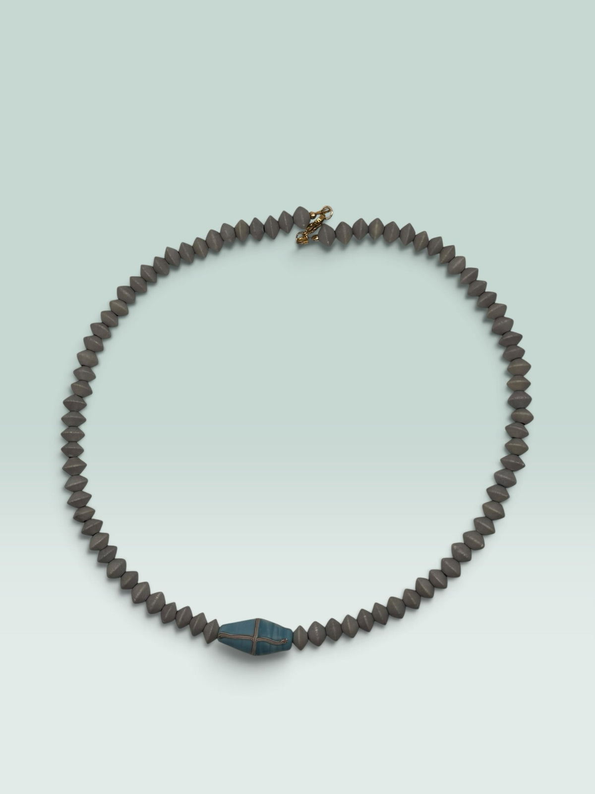 The Salty Bead Co handcrafted necklace with grey bicone beads and a central blue bead featuring metallic cross-hatching