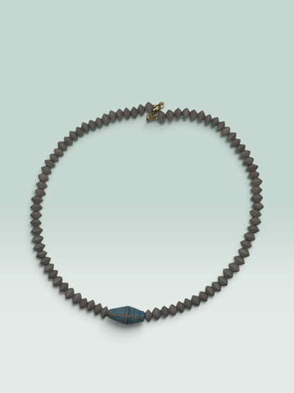 The Salty Bead Co handcrafted necklace with grey bicone beads and a central blue bead featuring metallic cross-hatching