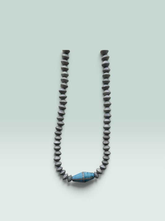 The Salty Bead Co handcrafted necklace featuring grey bicone beads and a central blue bead with metallic detailing.