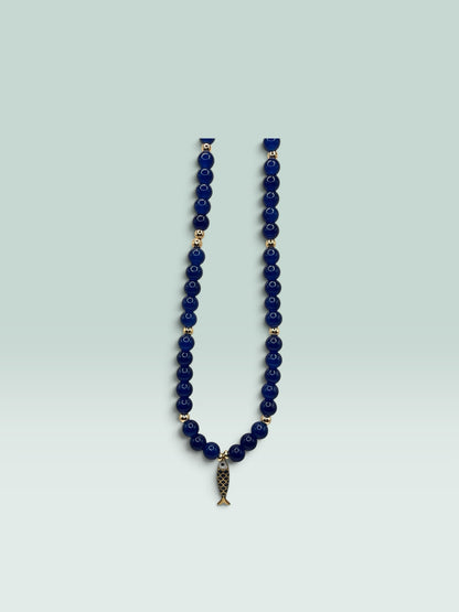 The Salty Bead Co navy blue beaded necklace with gold-tone spacers and a whimsical fish charm pendant.