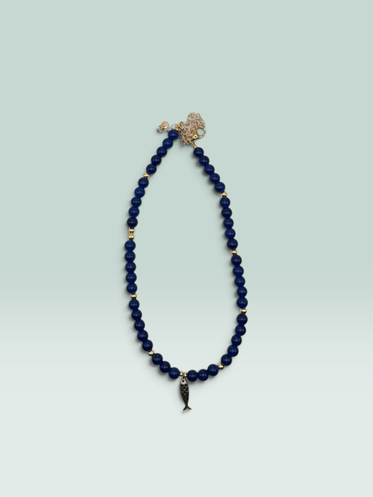The Salty Bead Co navy blue beaded necklace with gold-tone spacers and a whimsical fish charm pendant.