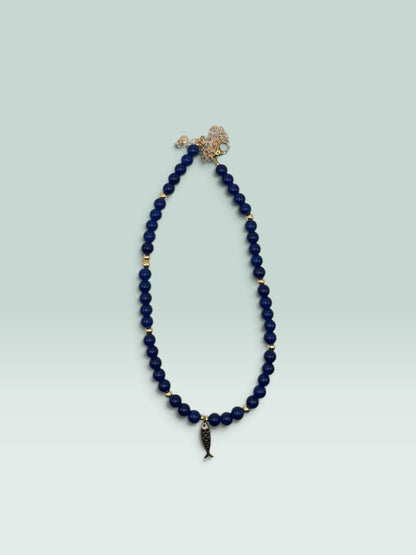 The Salty Bead Co navy blue beaded necklace with gold-tone spacers and a whimsical fish charm pendant.