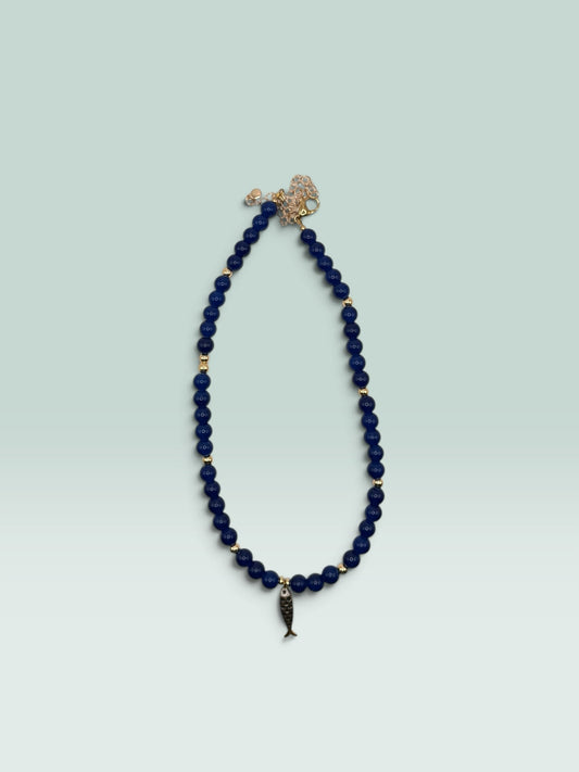 The Salty Bead Co navy blue beaded necklace with gold-tone spacers and a whimsical fish charm pendant.