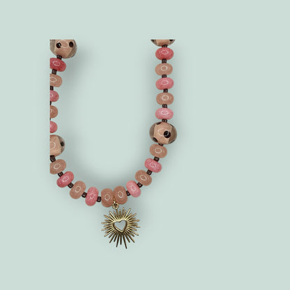 The Salty Bead Co beaded necklace featuring pink and rose round beads with a gold-tone sunburst heart pendant.