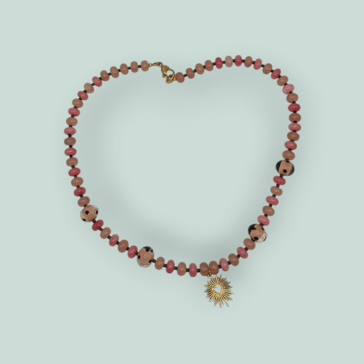 The Salty Bead Co beaded necklace featuring pink and rose beads with a gold-tone sunburst heart pendant