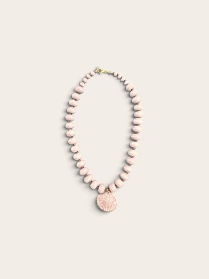 The Salty Bead Co coastal necklace with dusty-pink matte beads and a gold-edged natural seashell pendant.