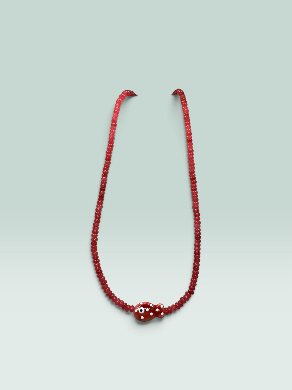 The Salty Bead Co red beaded necklace featuring a whimsical fish pendant with white polka dots and an evil eye detail.
